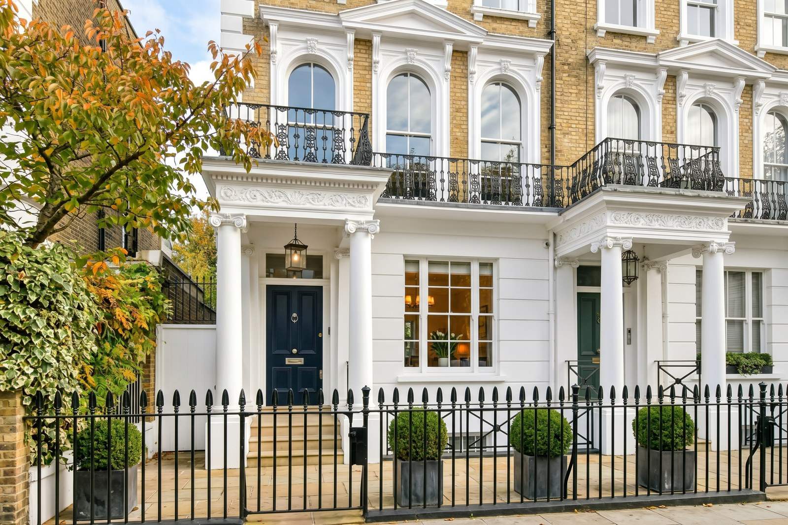 White stucco house with black railings and a front garden