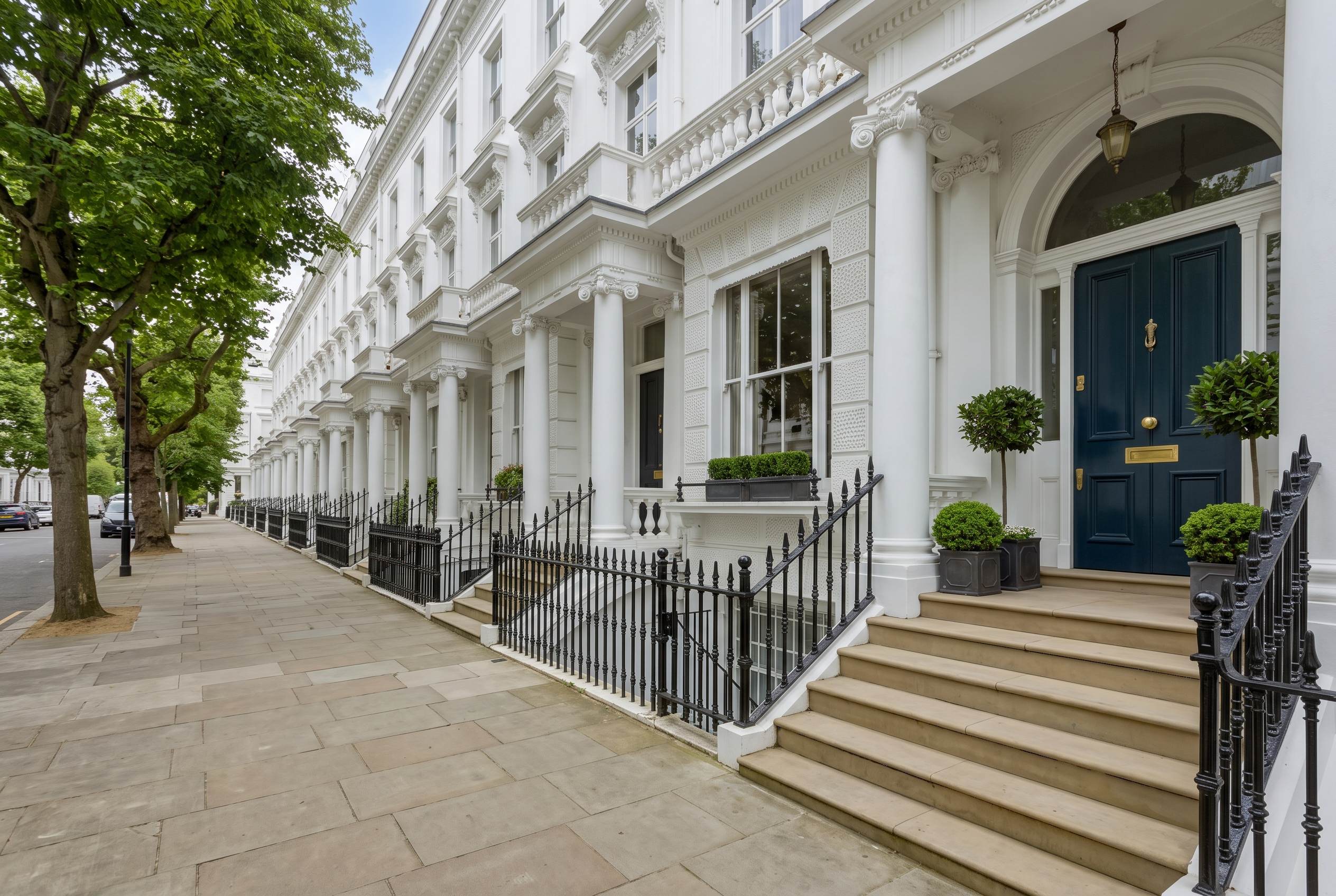 White stucco townhouses with black railings on a London street