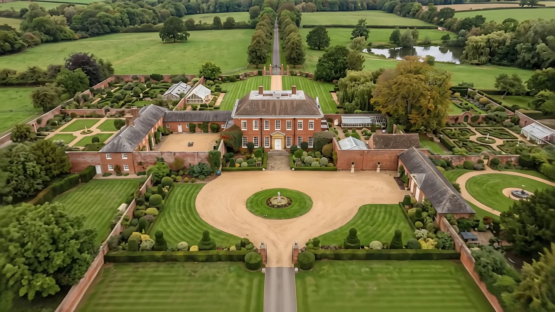 Aerial view of a red-brick country house with formal gardens and parkland